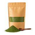 Kraft pouch of Veggie Pure spinach powder with a window showing the deep green powder, a heap of powder and a wooden spoon in front